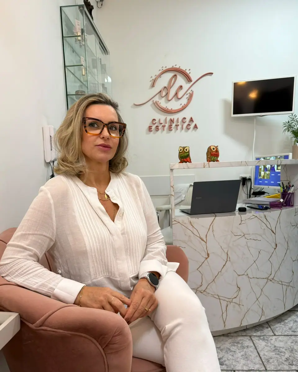 Dina Costa de óculos, sentada na poltrona rosa da clínica
